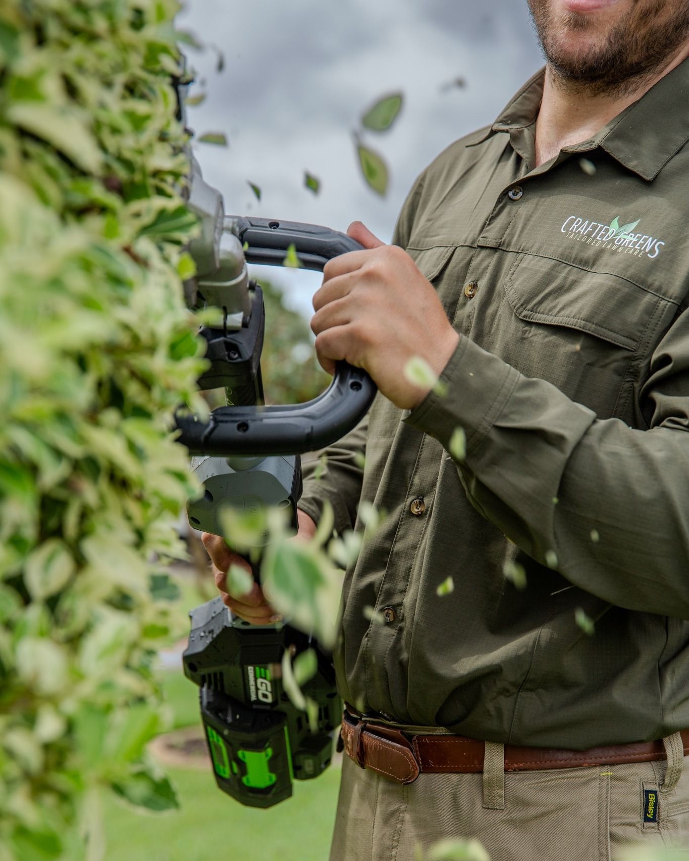 Man Trimming a Hedge With a Power Tool, Greenery and Leaves Flying — Mow & Mulch Lawn & Garden Maintenance In Corlette, NSW