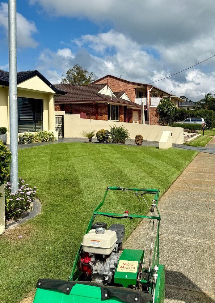 Green lawn mower in front of a suburban house with freshly cut grass on a sunny day — Mow & Mulch Lawn & Garden Maintenance In Nelson Bay, NSW