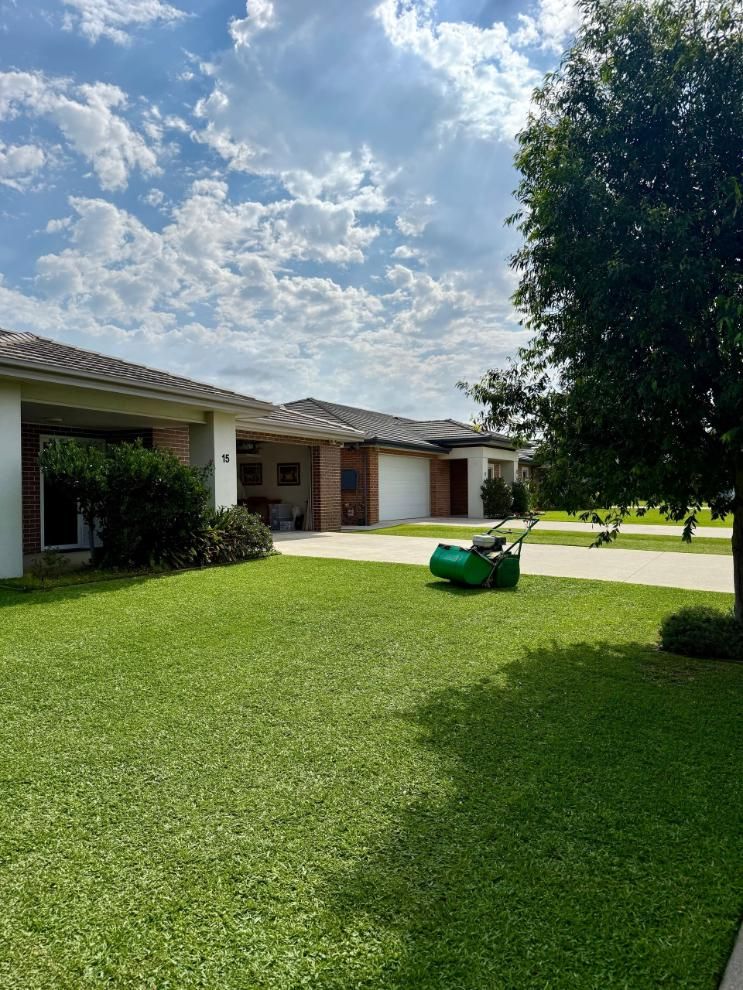 Suburban front lawn with a green lawn mower under a partly cloudy sky — Mow & Mulch Lawn & Garden Maintenance In Nelson Bay, NSW