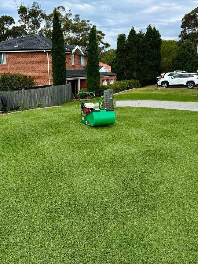 Lawn mower on a green suburban lawn near brick houses and parked cars — Mow & Mulch Lawn & Garden Maintenance In Nelson Bay, NSW