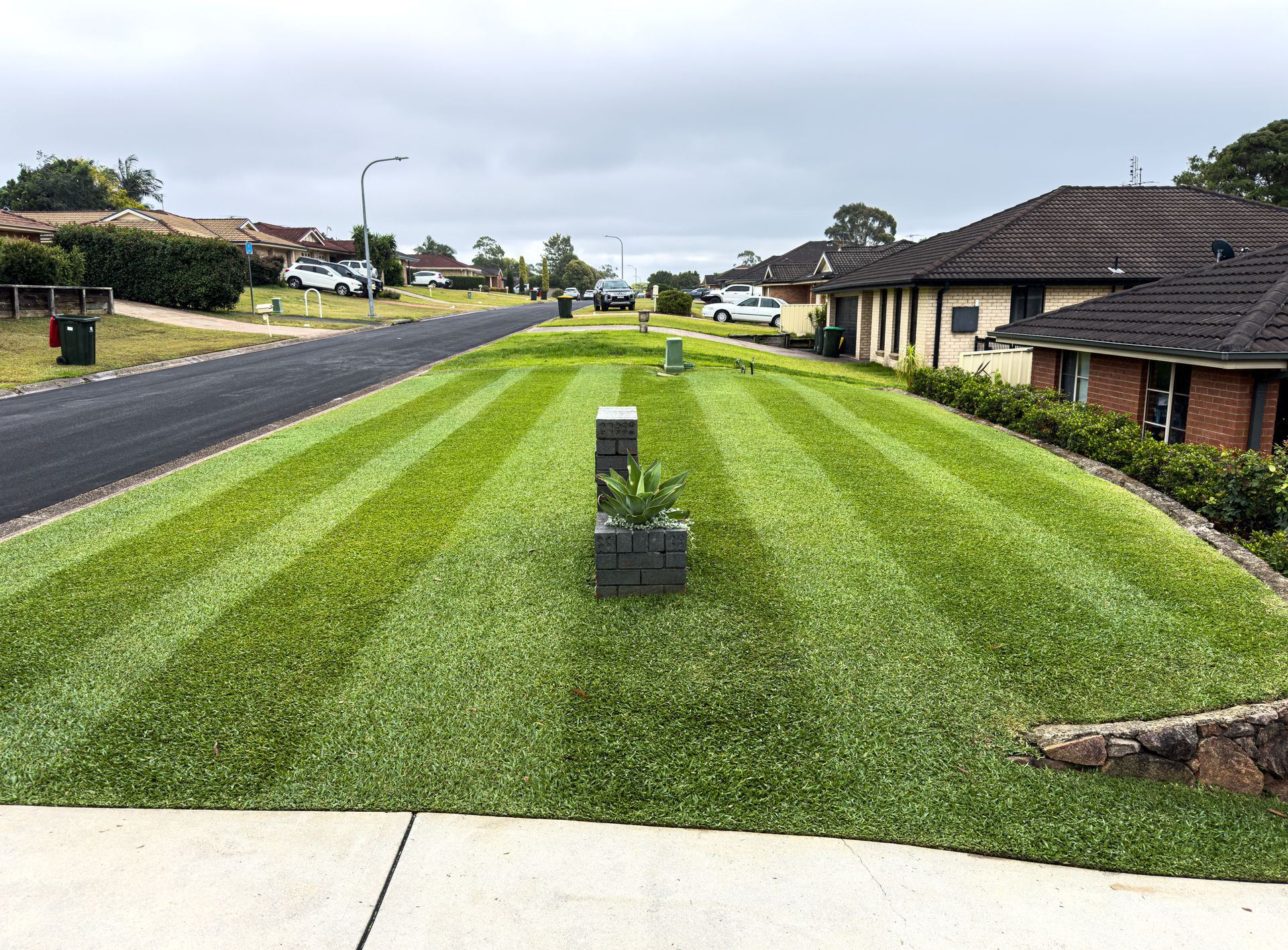 Green Lawn and a Sidewalk in Front of a White Building — Mow & Mulch Lawn & Garden Maintenance In Salamander Bay, NSW