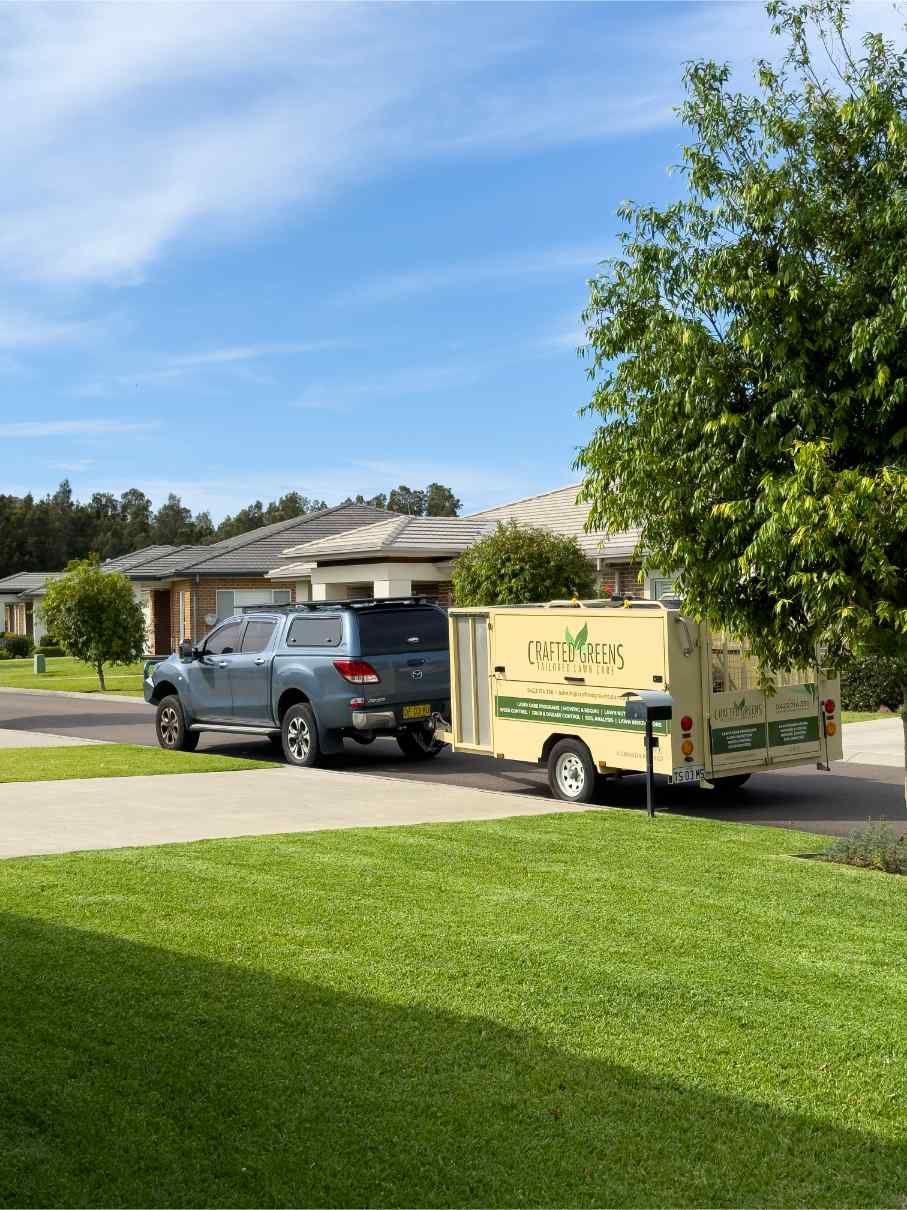 Blue Truck Towing a Beige Trailer in Front of Houses on a Sunny Day — Mow & Mulch Lawn & Garden Maintenance In Medowie, NSW