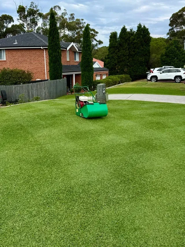 Lawn mower on a green suburban lawn near houses and a parked white SUV — Mow & Mulch Lawn & Garden Maintenance In Nelson Bay, NSW