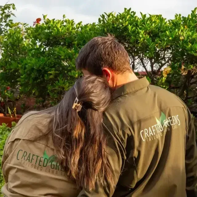 Couple in Matching Green Shirts Embracing Outdoors Against Green Foliage — Mow & Mulch Lawn & Garden Maintenance In Salamander Bay, NSW