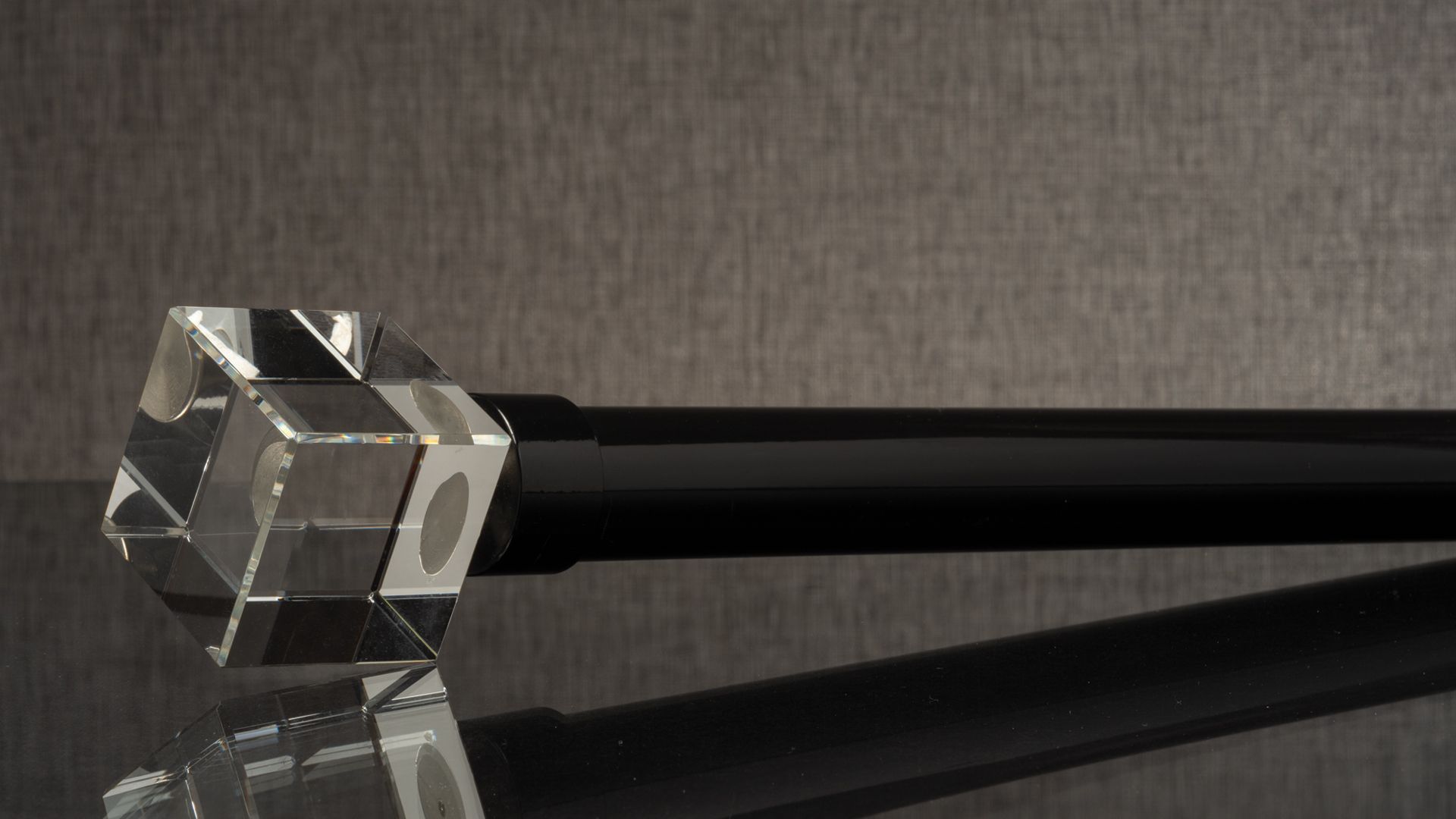 Transparent cube with black rods on a dark reflective surface