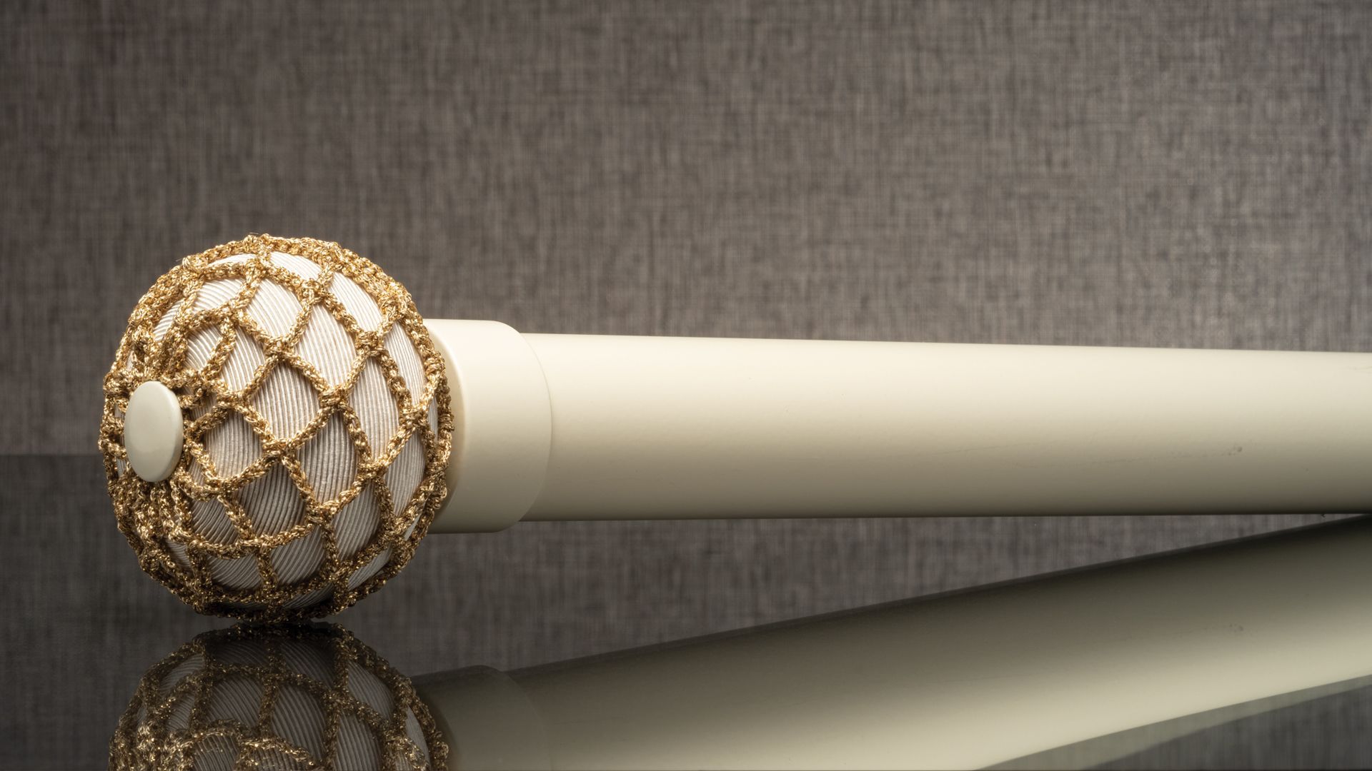 Decorative gold-and-ivory scepter with a jeweled orb on a reflective surface