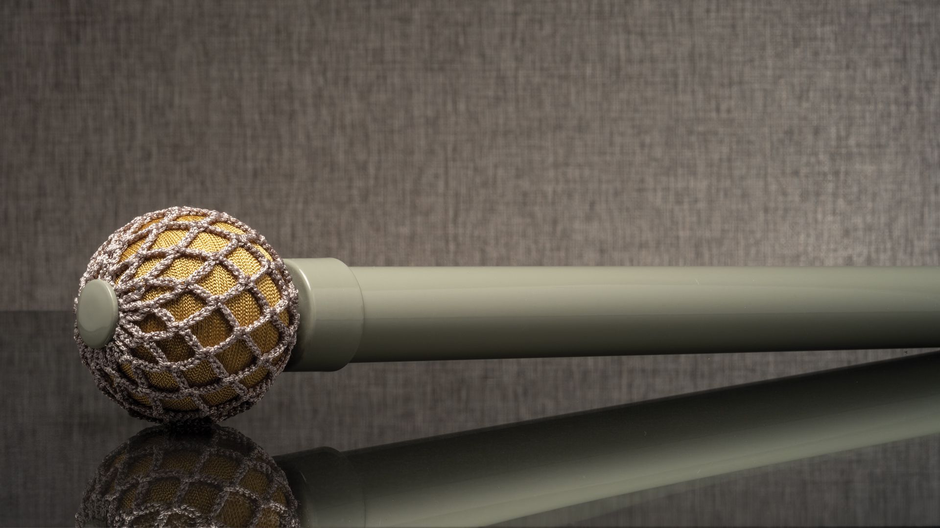 Decorative gold and crystal microphone resting on a sleek gray surface against a textured gray background