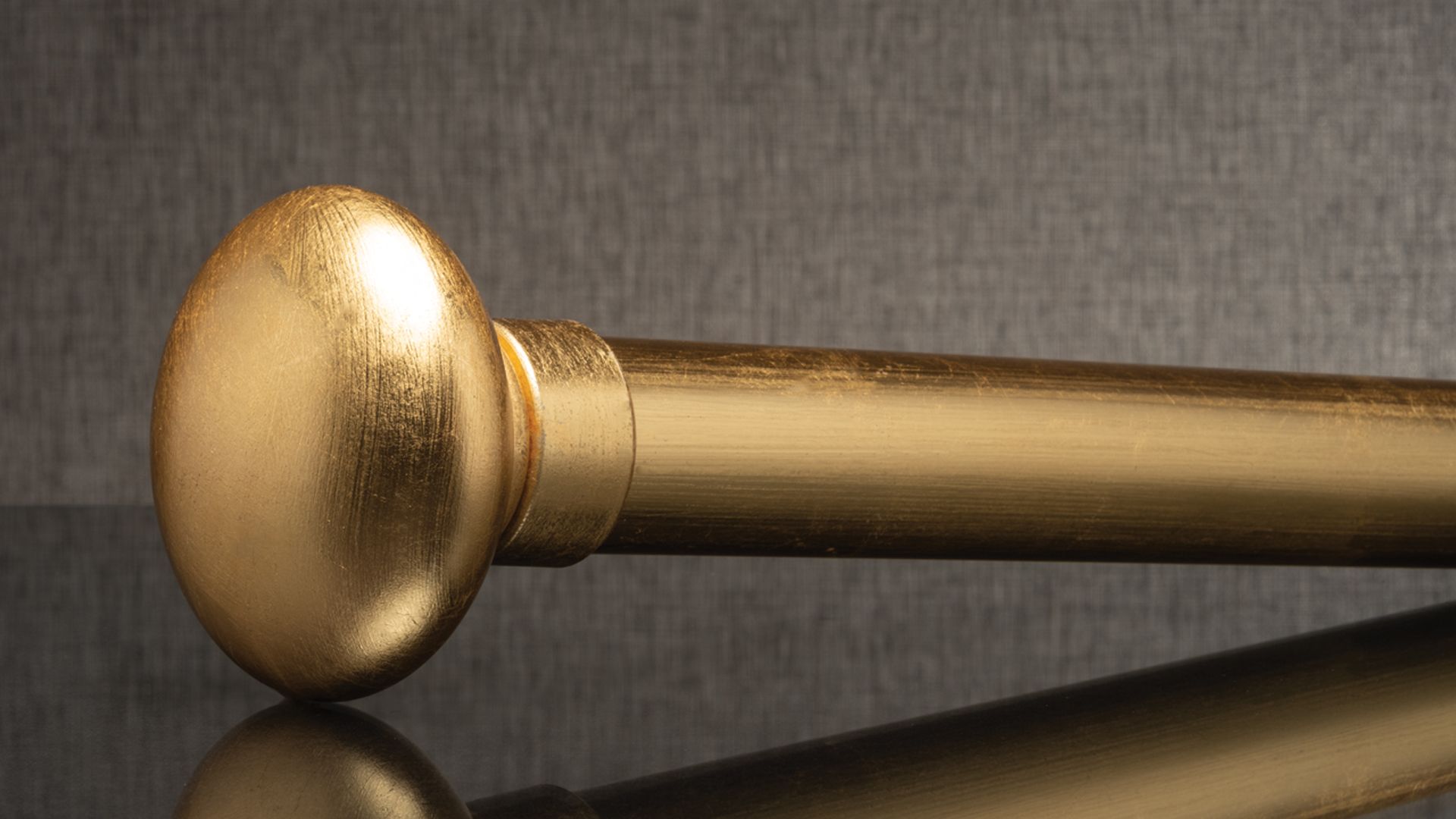 Gold curtain rod end cap on a dark reflective surface