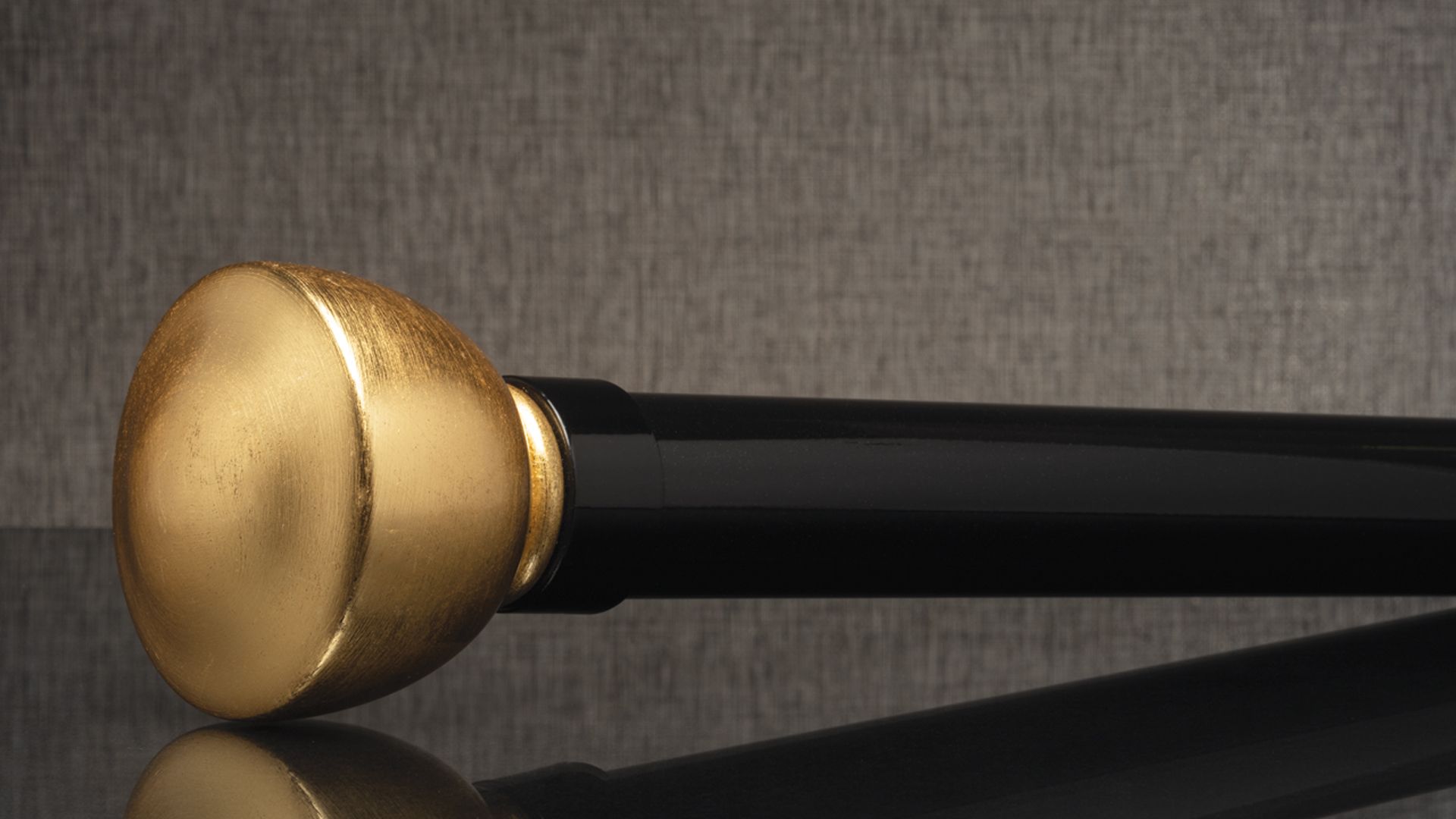 Gold-capped black cane handle on a gray textured background