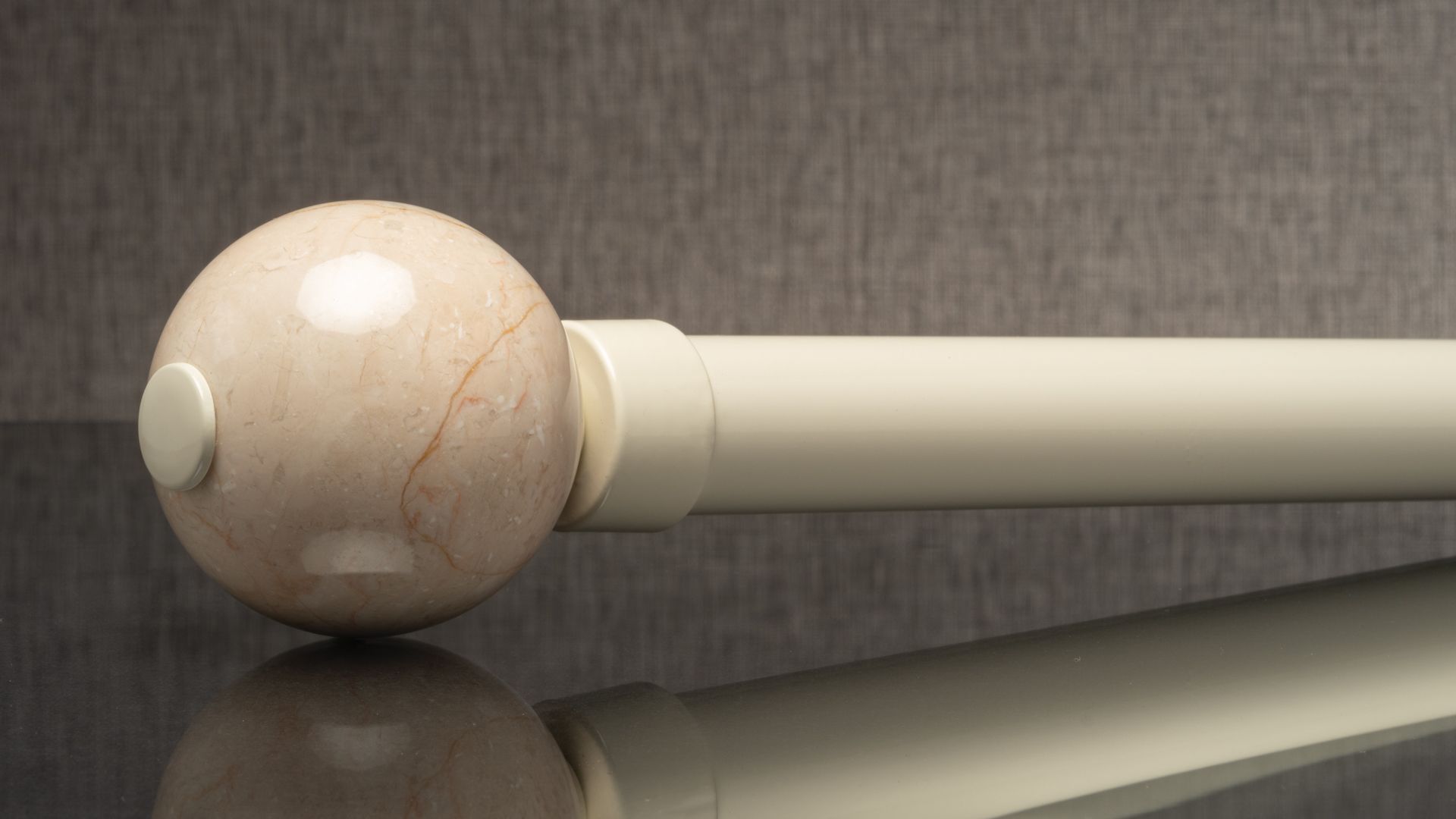 Close-up of a white baton with a marble-like round head on a reflective surface.