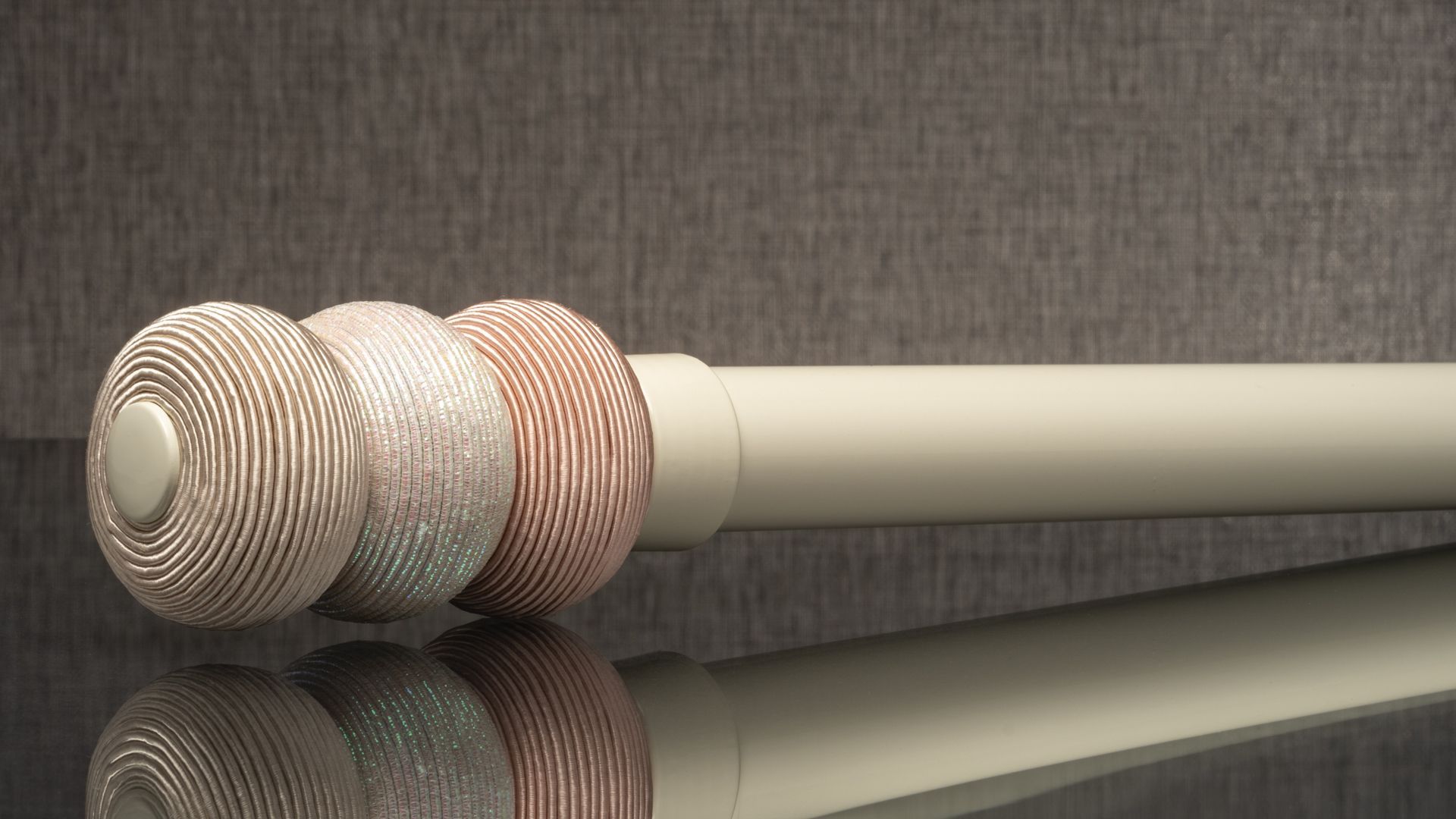 Three textured round wooden handles on a beige rod, reflected on a glossy black surface.