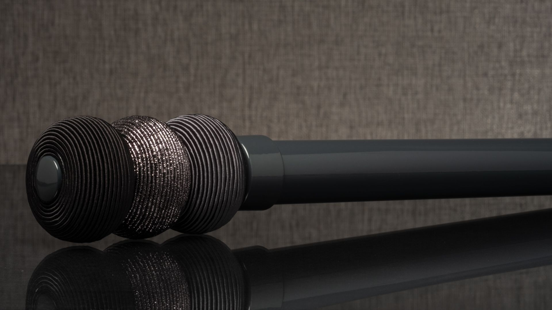 Black and silver microphone resting on a reflective surface against a dark background