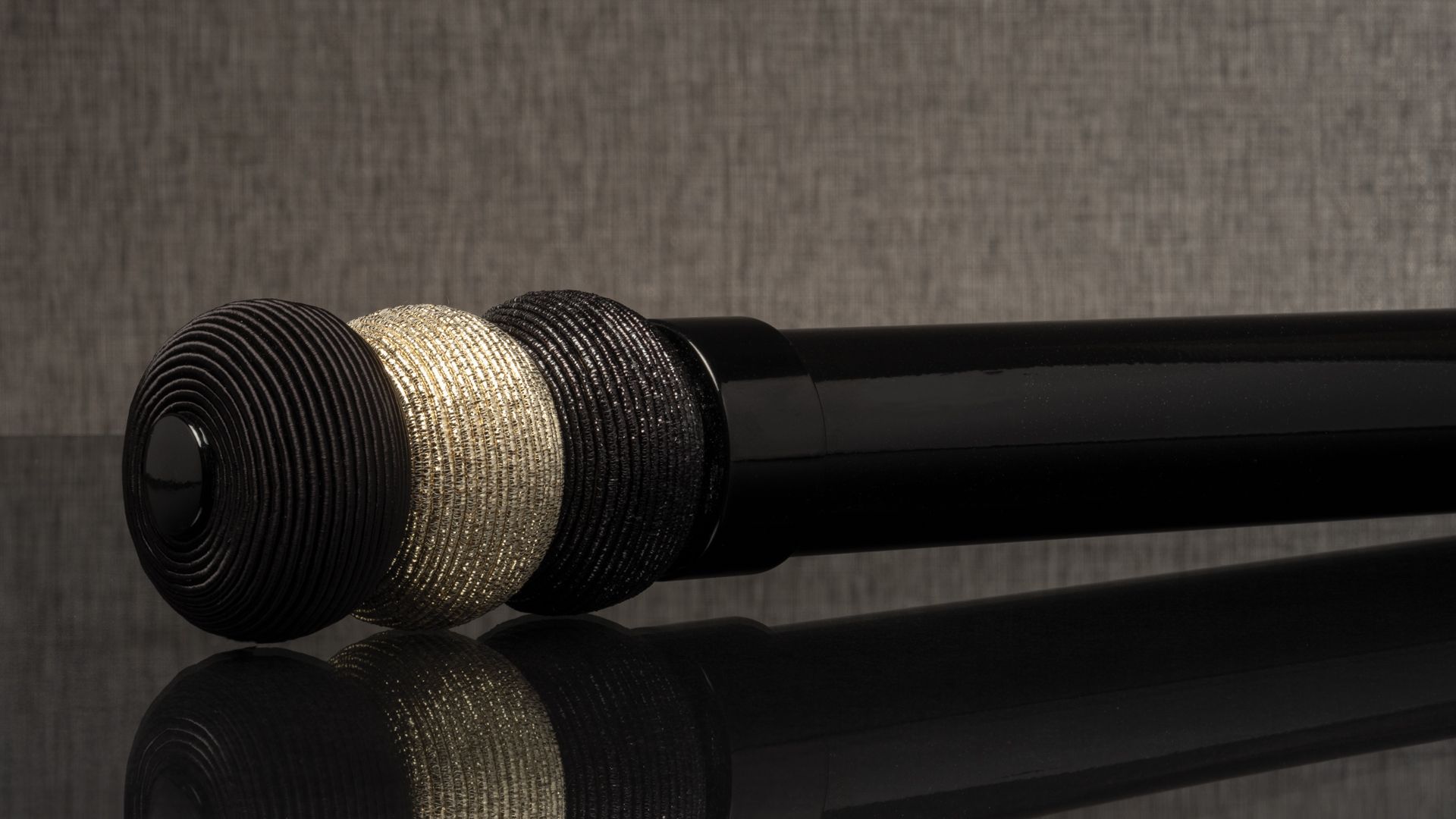 Three decorative microphone heads on a black rod against a gray background
