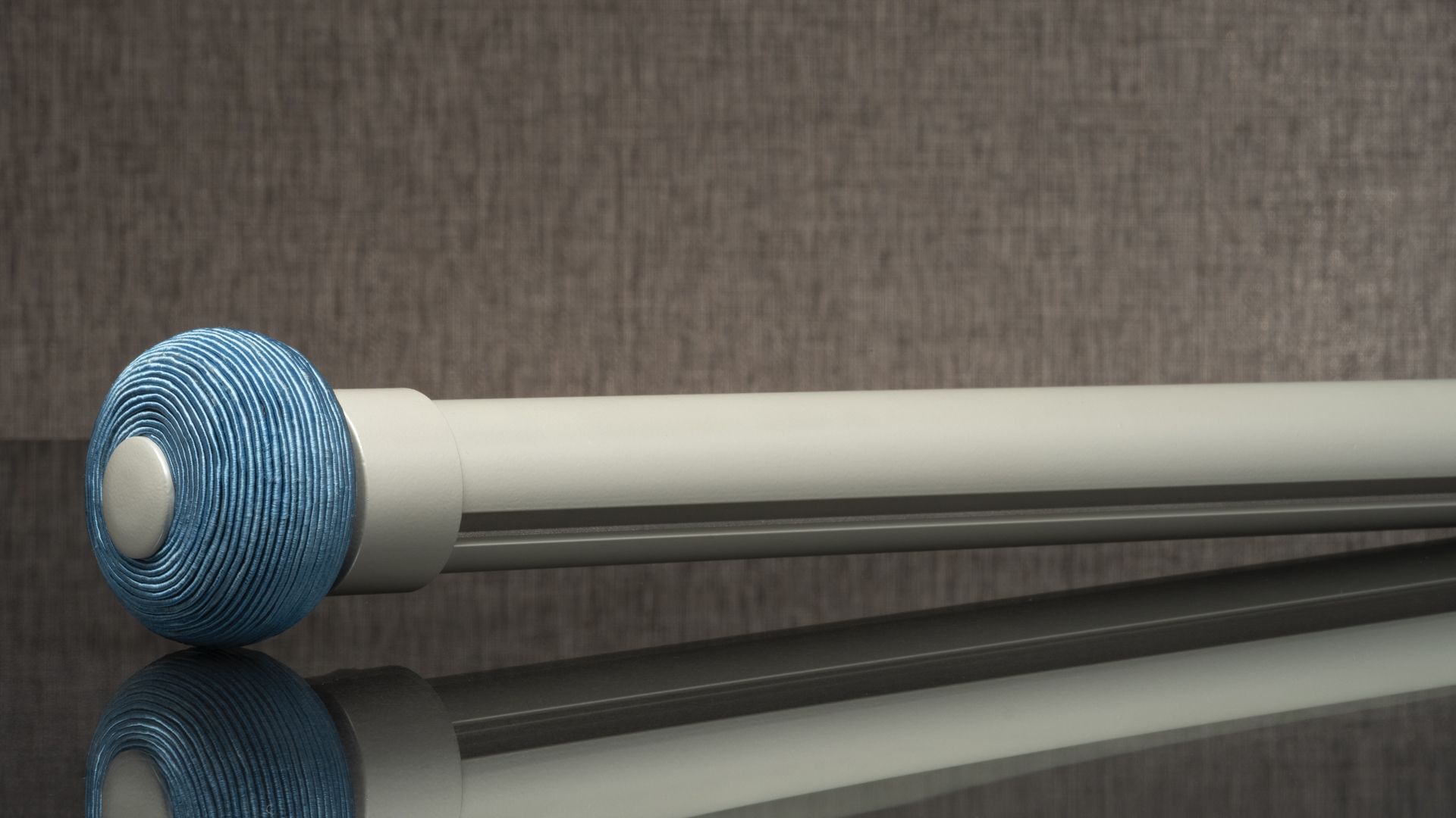Blue patterned ballpoint pen with a white barrel, lying on a reflective surface