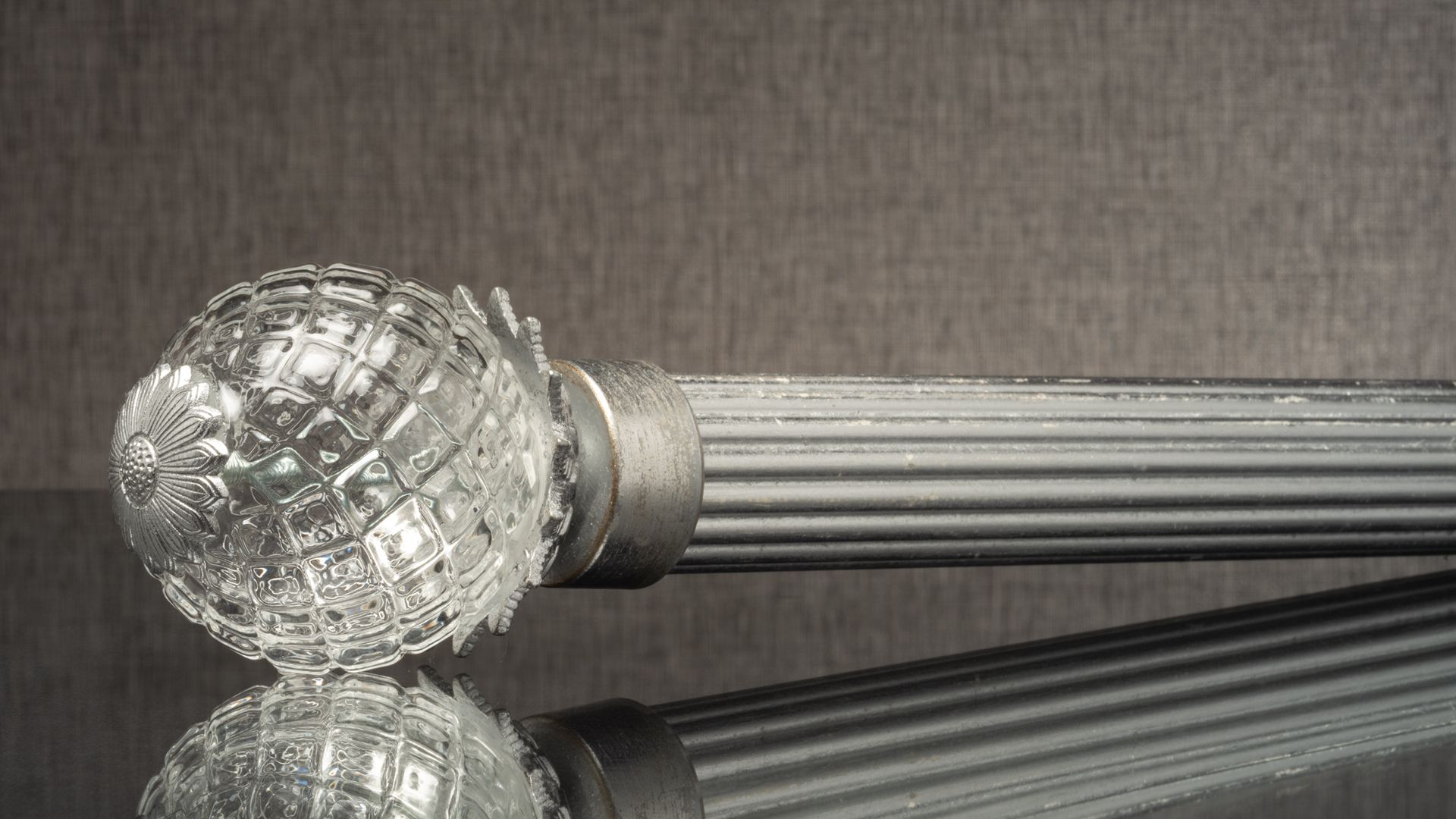 Crystal knob on a ribbed metallic handle against a dark gray background