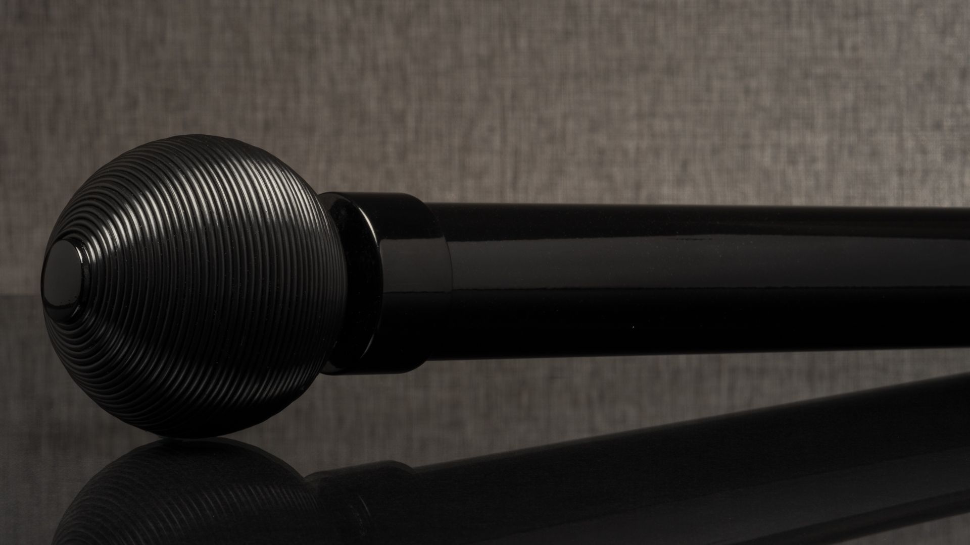 Black microphone on a reflective surface against a gray background.