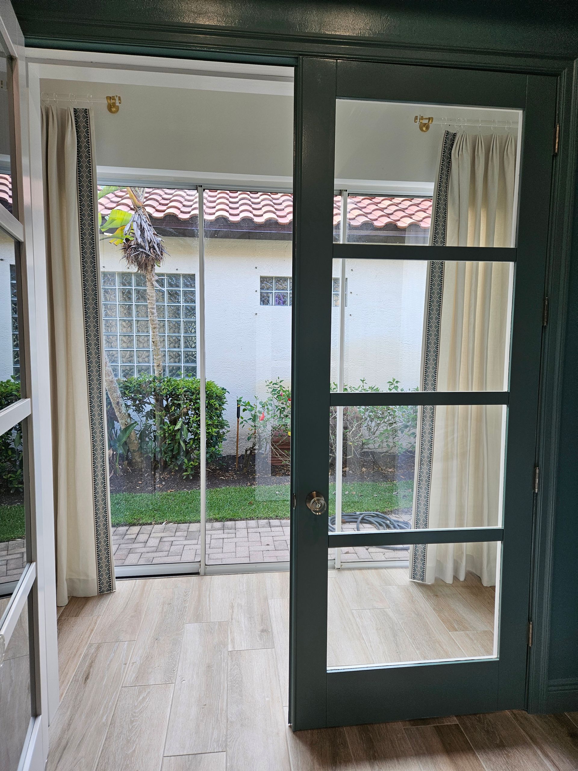 Open blue door and windows look out to a small courtyard with plants and a tiled roof.