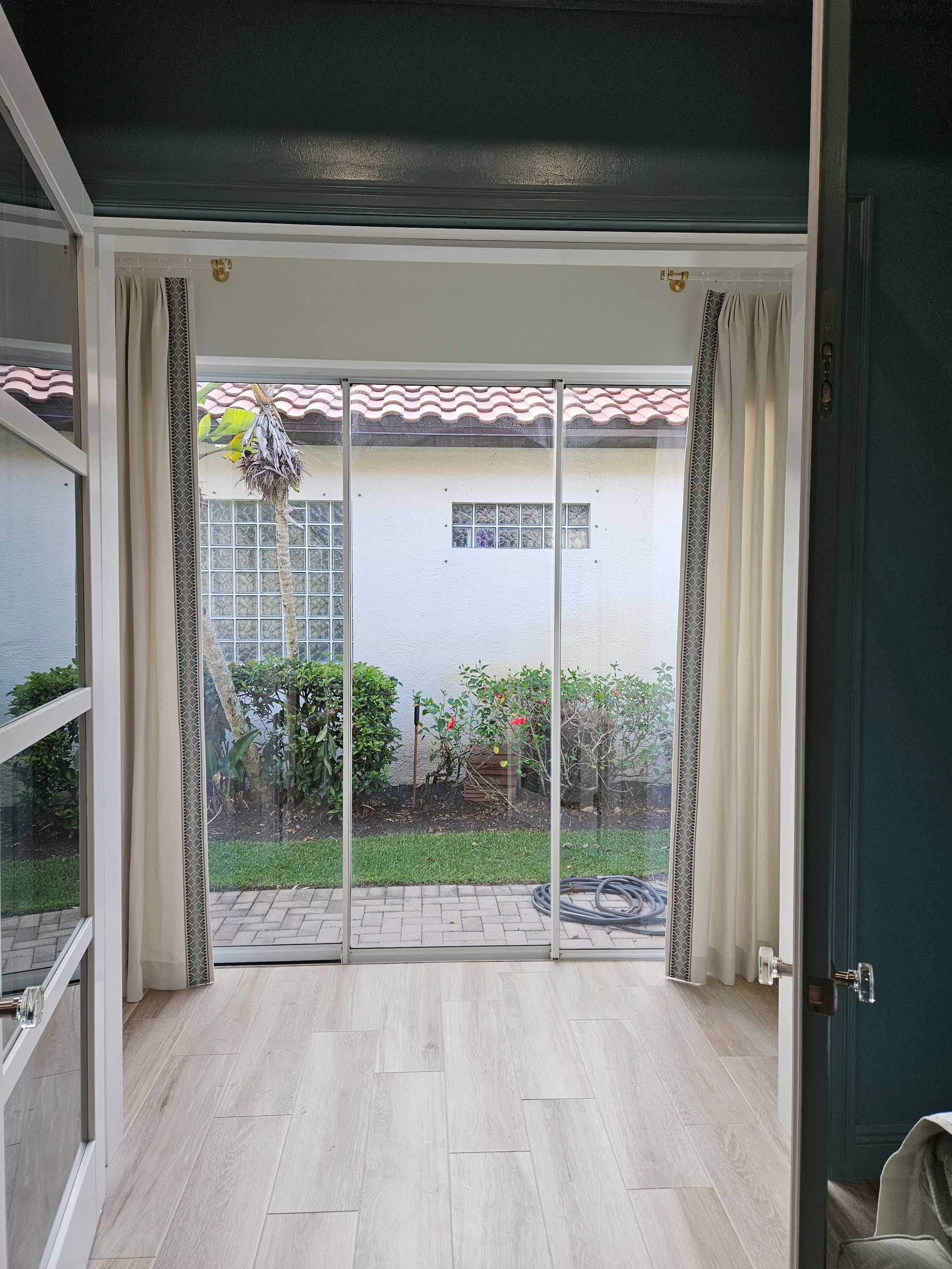 Empty room with light wood floor, open sliding glass doors, and a view of a garden outside