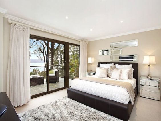 Bright bedroom with a king bed, sliding glass doors, and a view of trees and water