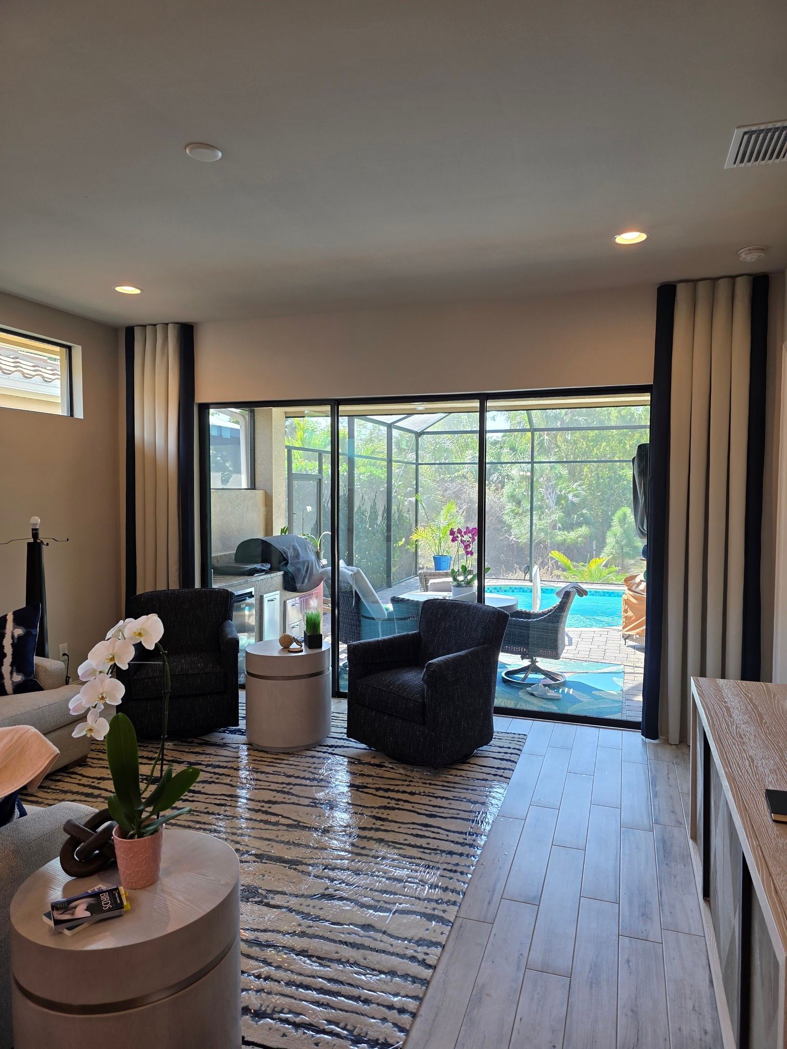 Modern living room with sliding glass doors, patterned rug, and a view of a backyard pool