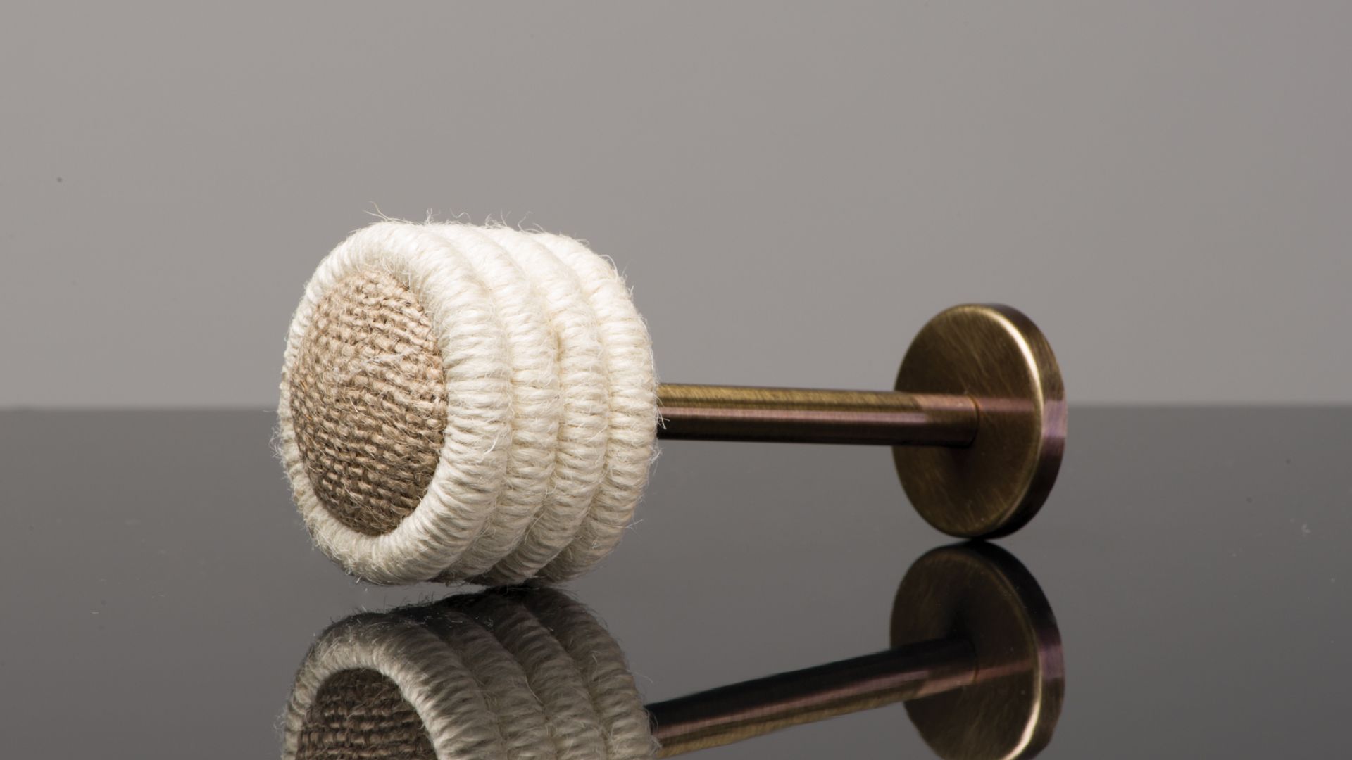 White and beige bath brush with a wooden handle lying on a reflective dark surface