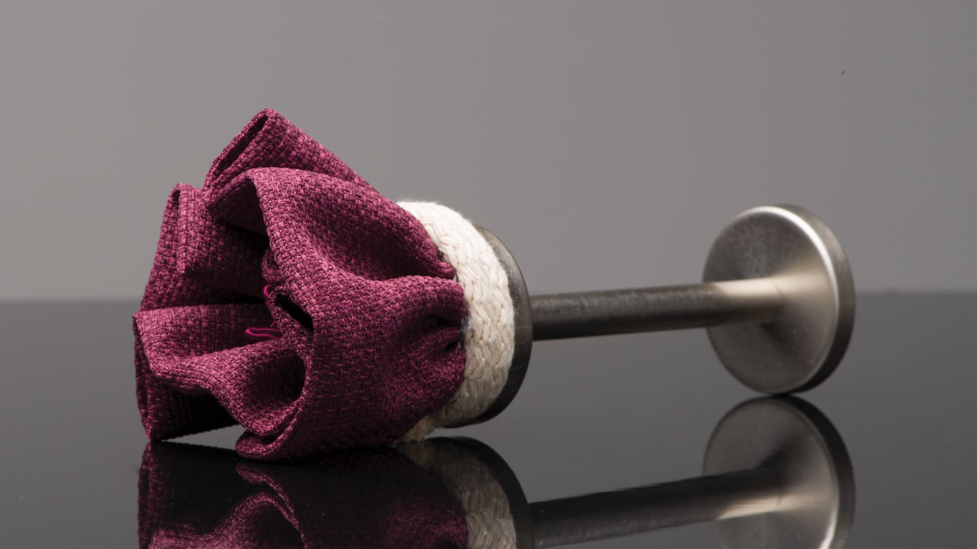 Purple wine stopper with a metallic handle lying on a reflective black surface