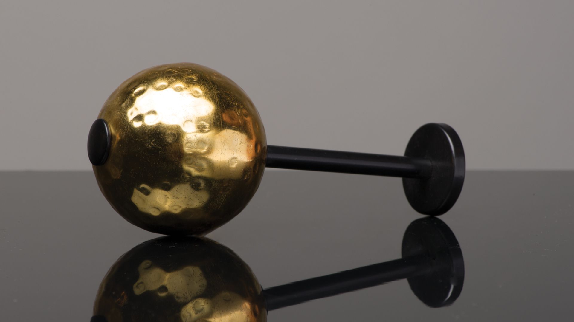 Gold and black decorative gavel lying on a reflective black surface
