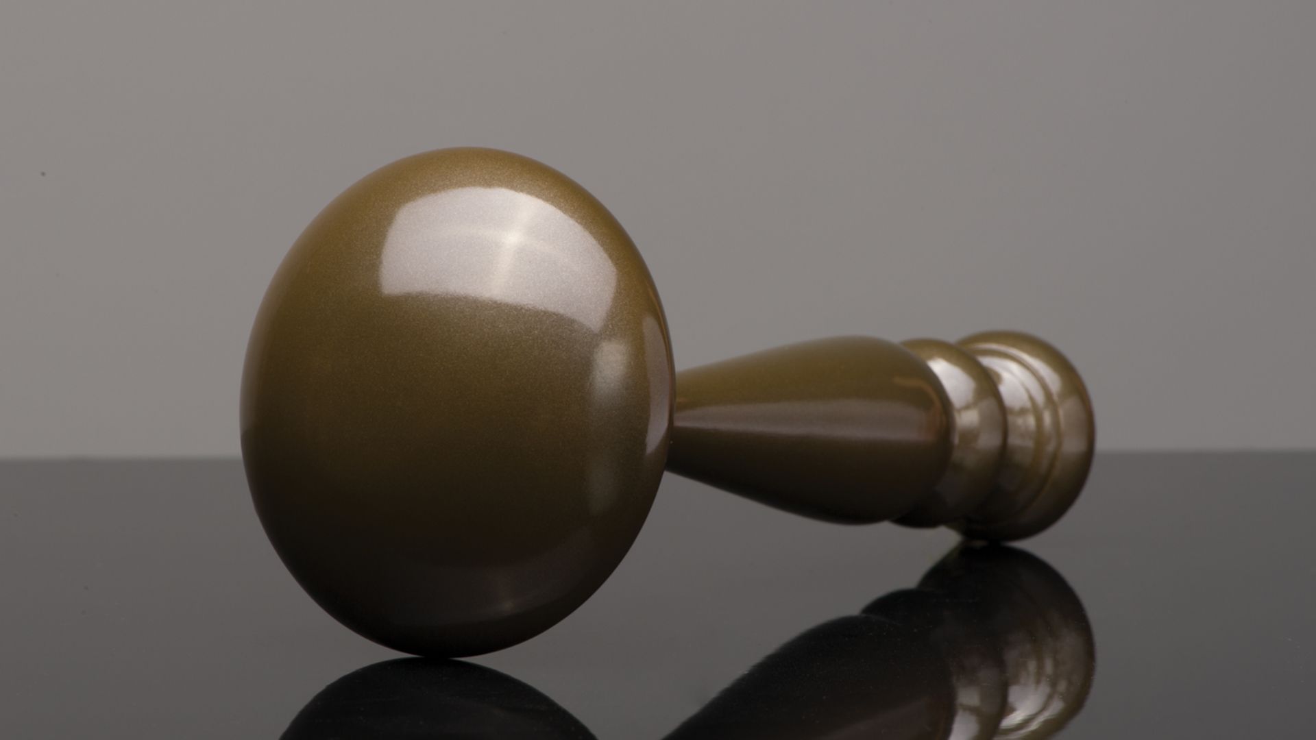 Wooden judge’s gavel lying on a reflective surface, brown with a dark handle.