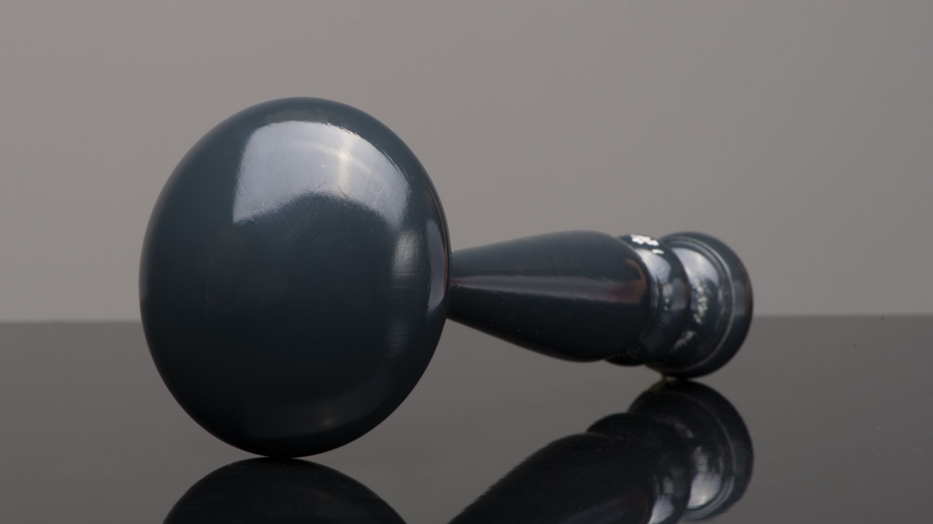 Black handheld massage gun lying on a reflective surface