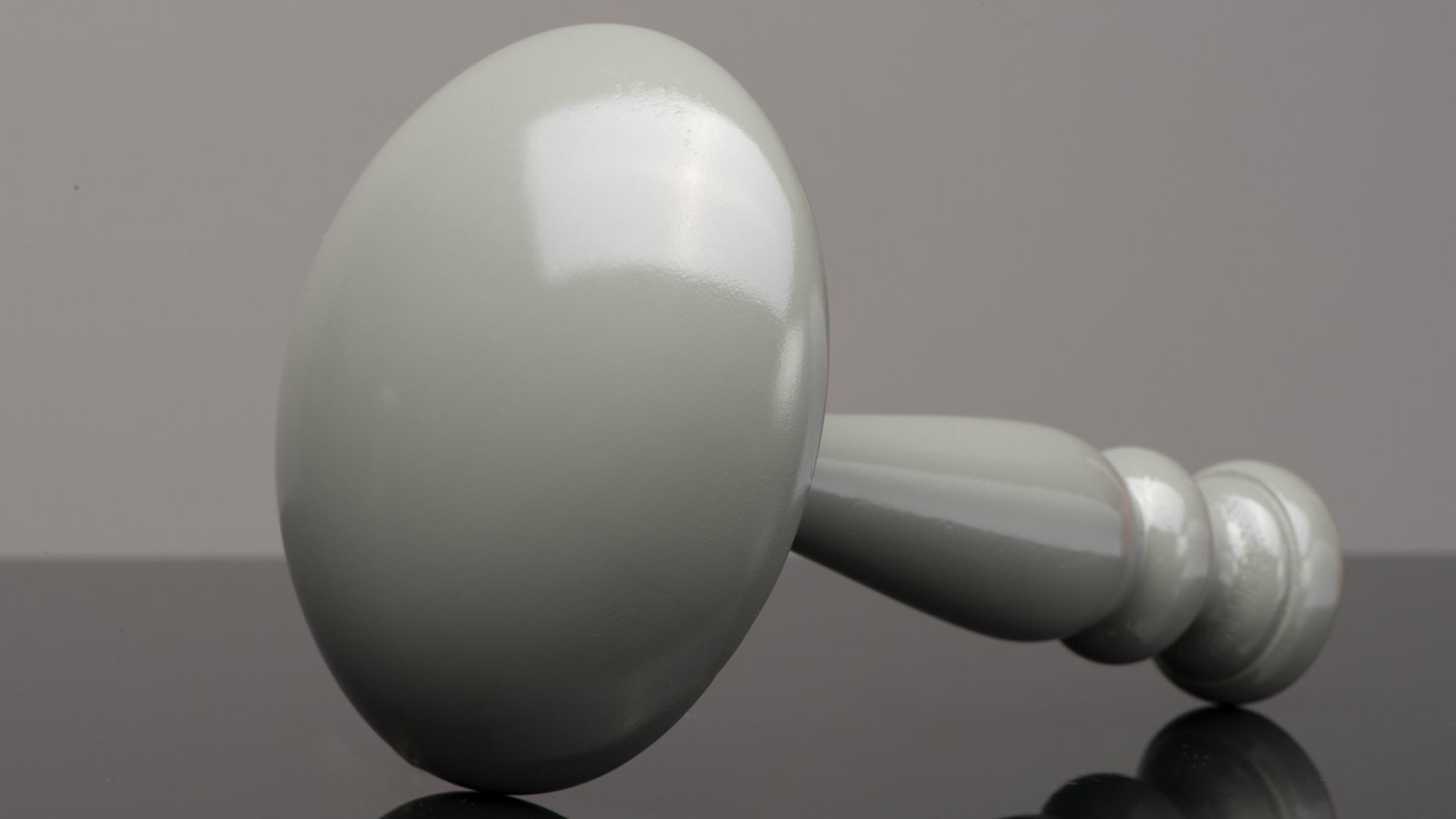 A shiny white spoon lying on a reflective dark surface