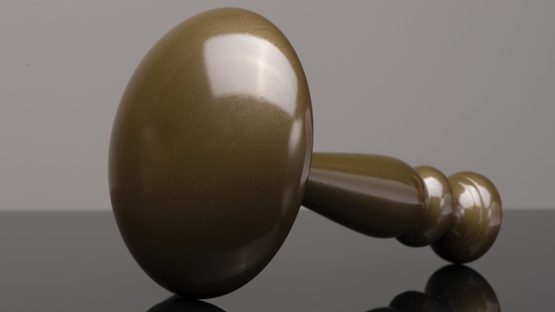 Brown wooden gavel lying on a reflective surface against a gray background