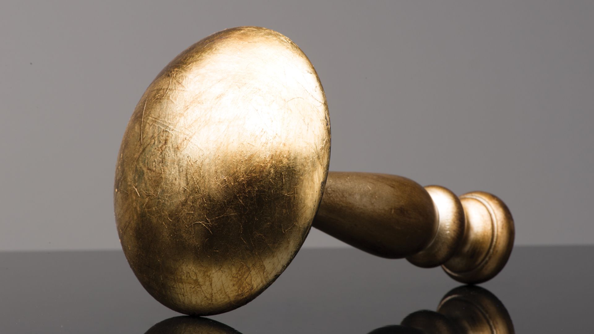 Golden wooden gavel lying on its side against a gray background