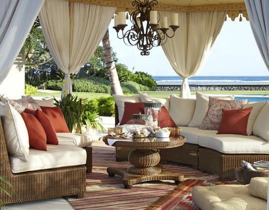 Elegant beachside patio with wicker seating, white curtains, and ocean view