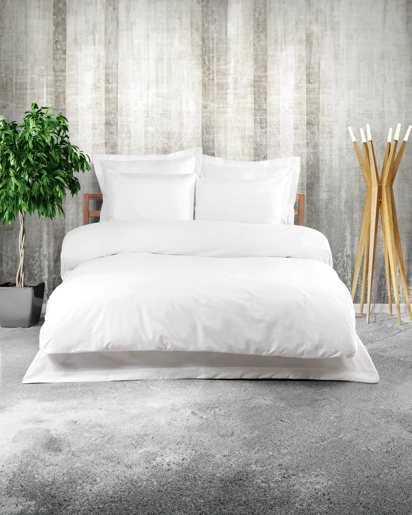 White bed with pillows in a modern bedroom, with a plant, gray rug, and wooden decor.