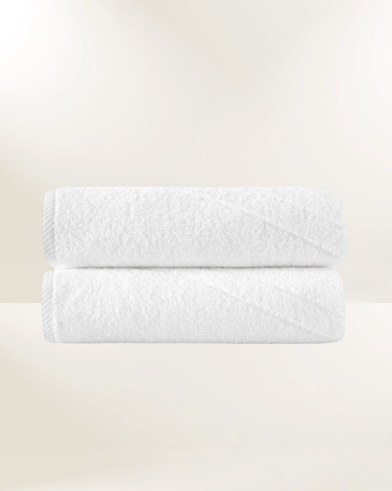 Two stacked white fluffy towels on a light beige background