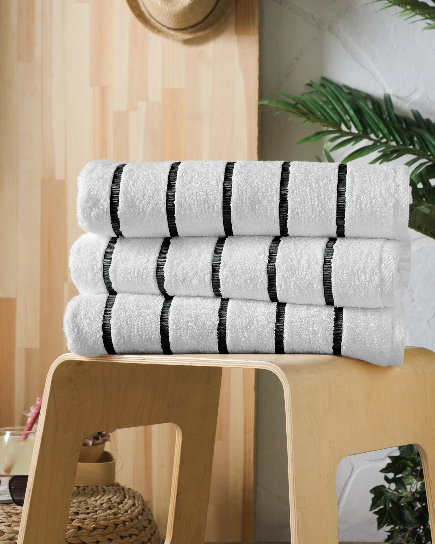 Stacked white towels with black stripes on a wooden stool in a spa-like room