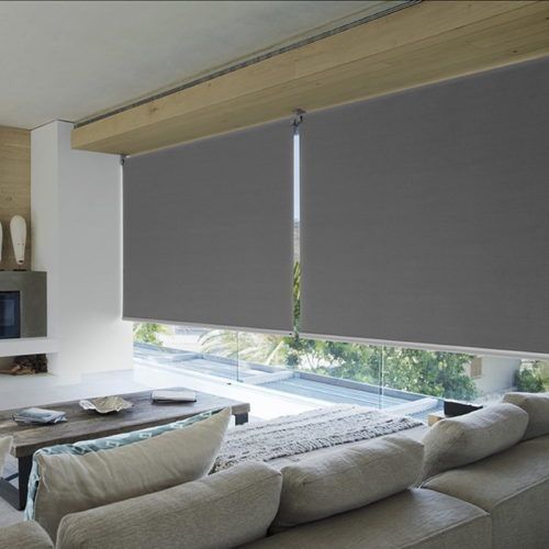 Modern living room with gray roller shades covering large windows and a beige sectional sofa