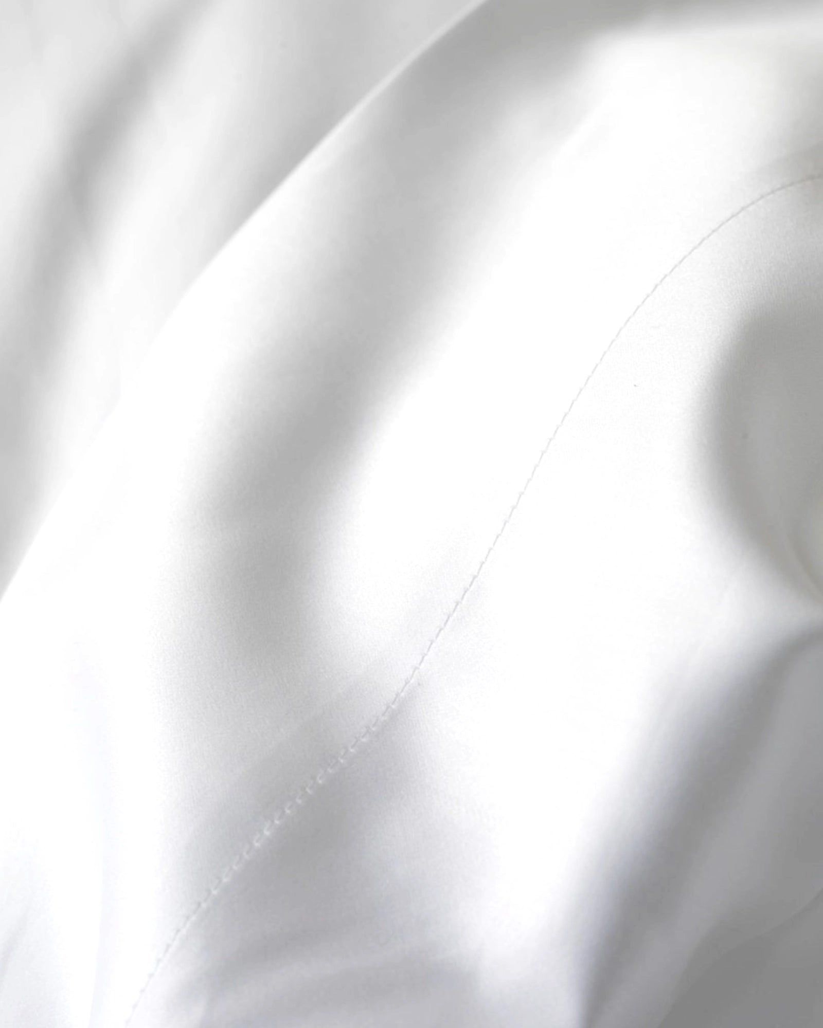Close-up of white fabric with soft folds and a stitched seam