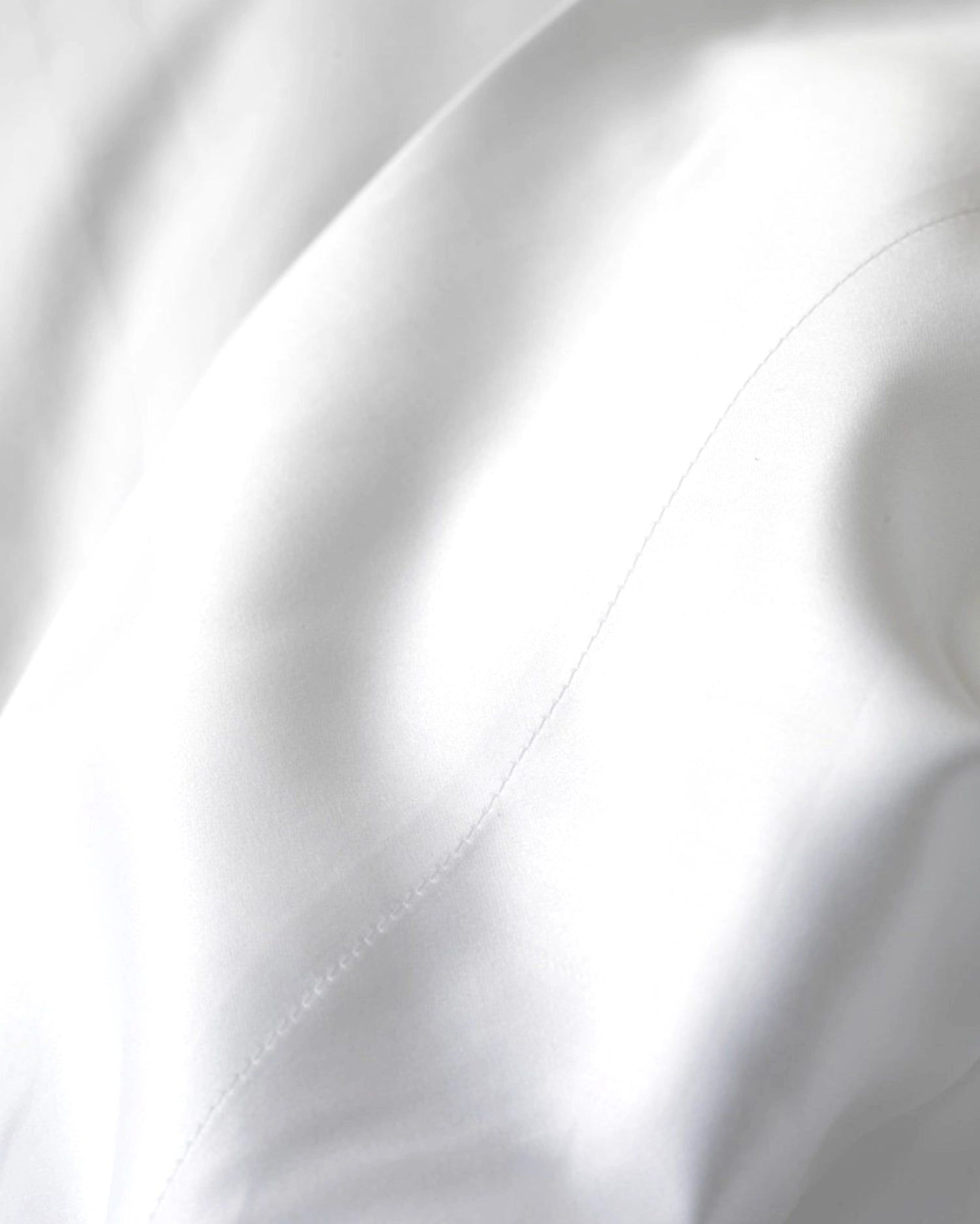 Close-up of smooth white fabric with soft folds and a curved seam line