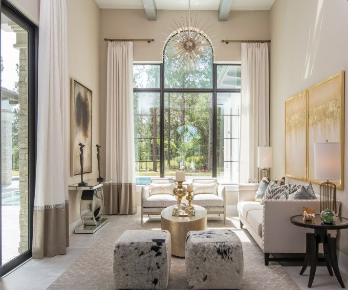 Elegant living room with tall arched window, white sofa, gold accents, and soft neutral decor