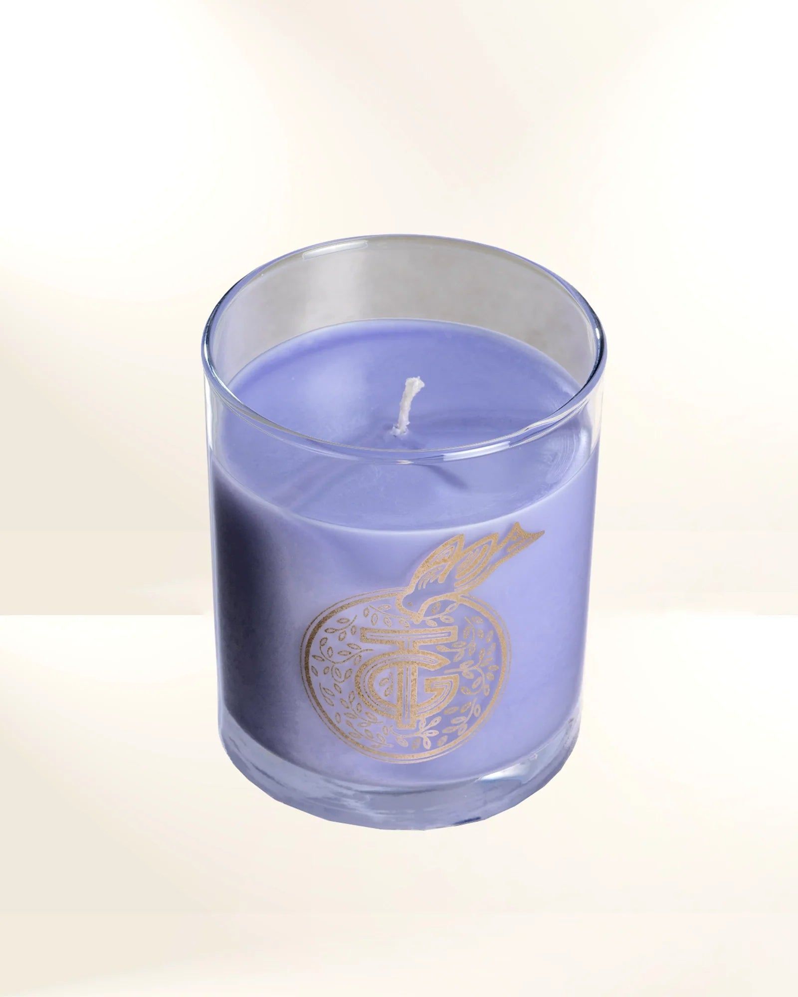 Purple candle in a clear glass jar with a decorative gold design