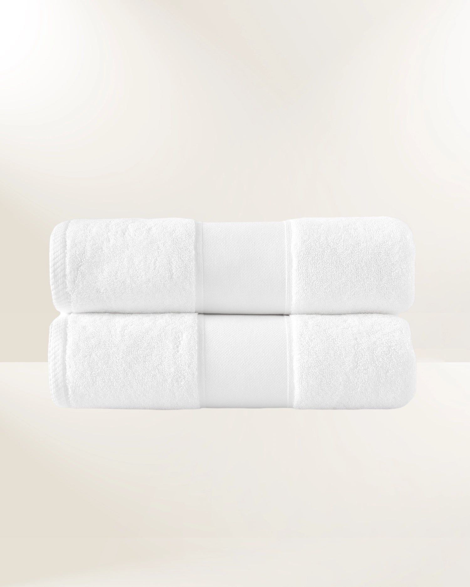 Stack of six white rolled towels on a light beige background