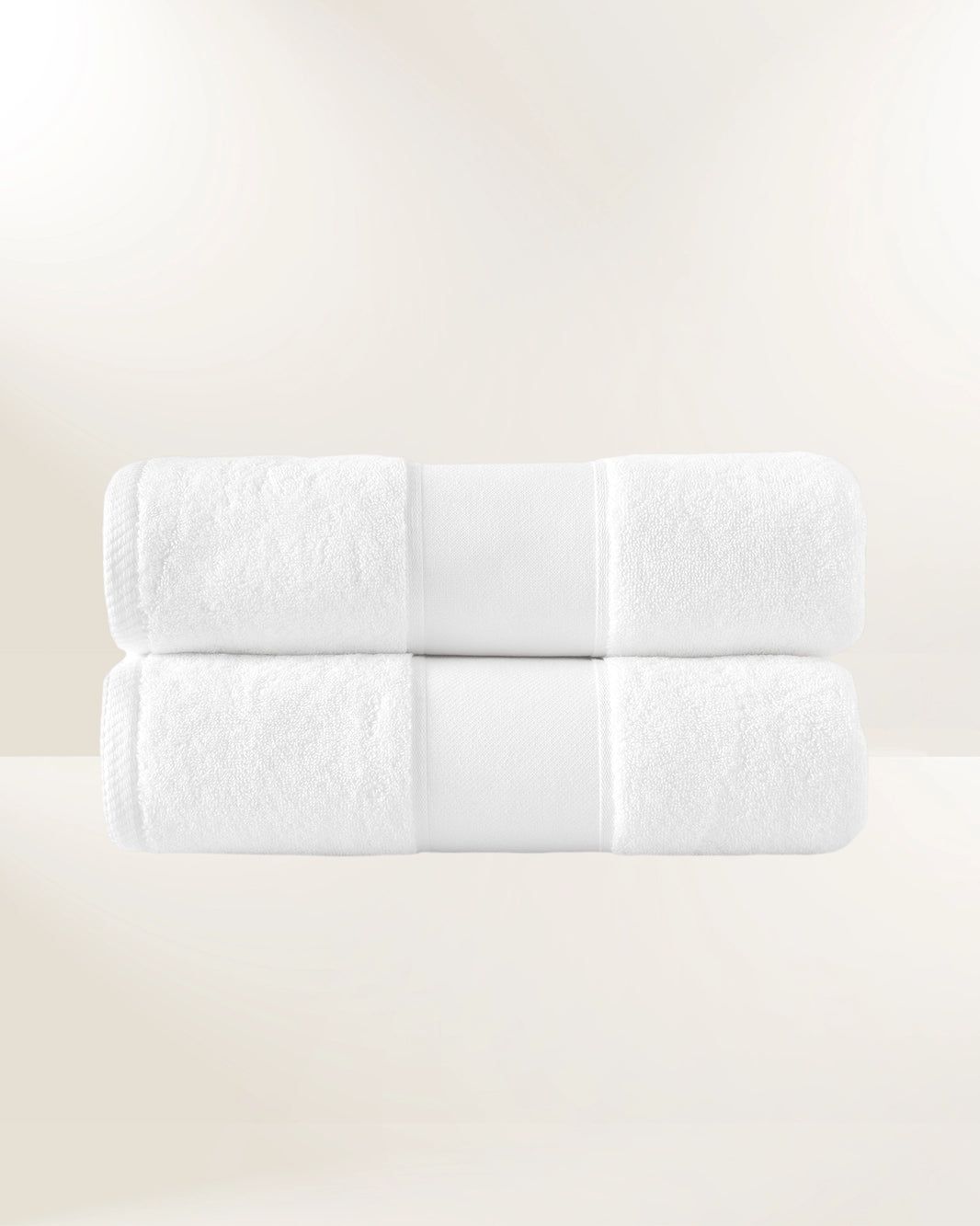 Stack of six rolled white towels on a light beige background