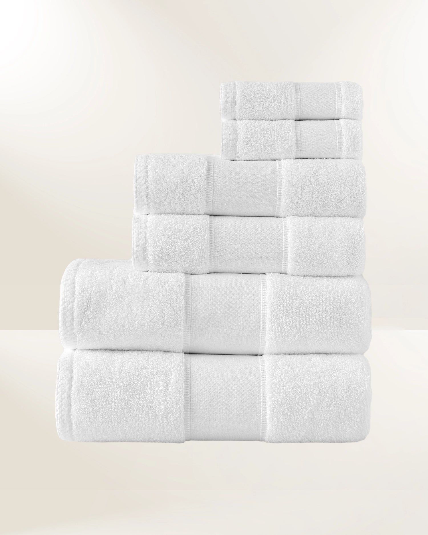 Stack of white folded towels arranged in a stepped pyramid on a light background