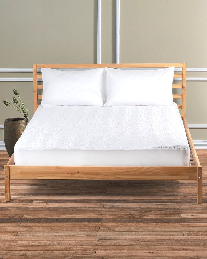 Wooden bed frame with white bedding in a bright room, on a wood floor.