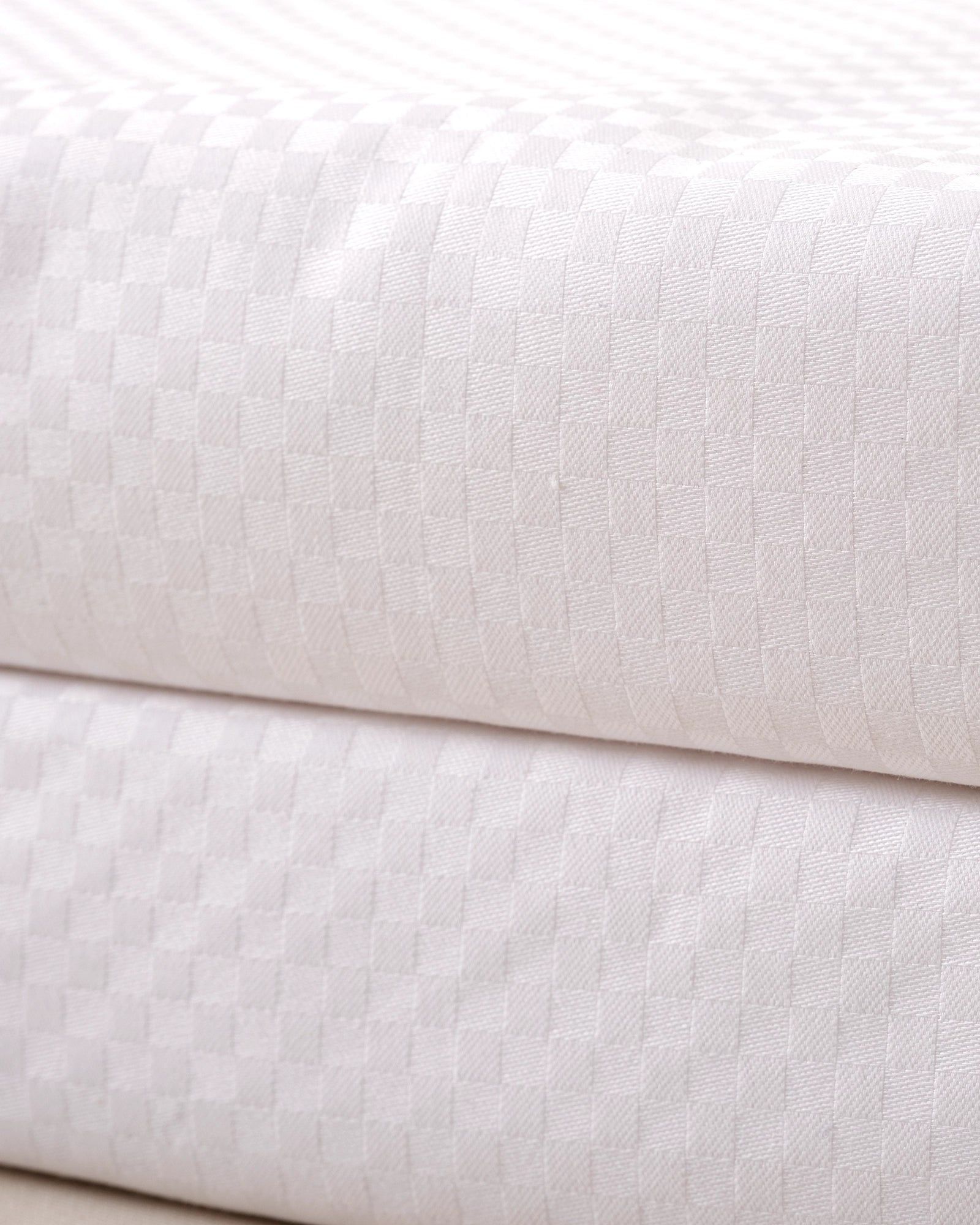 Close-up of folded white textured fabric with a soft diagonal seam