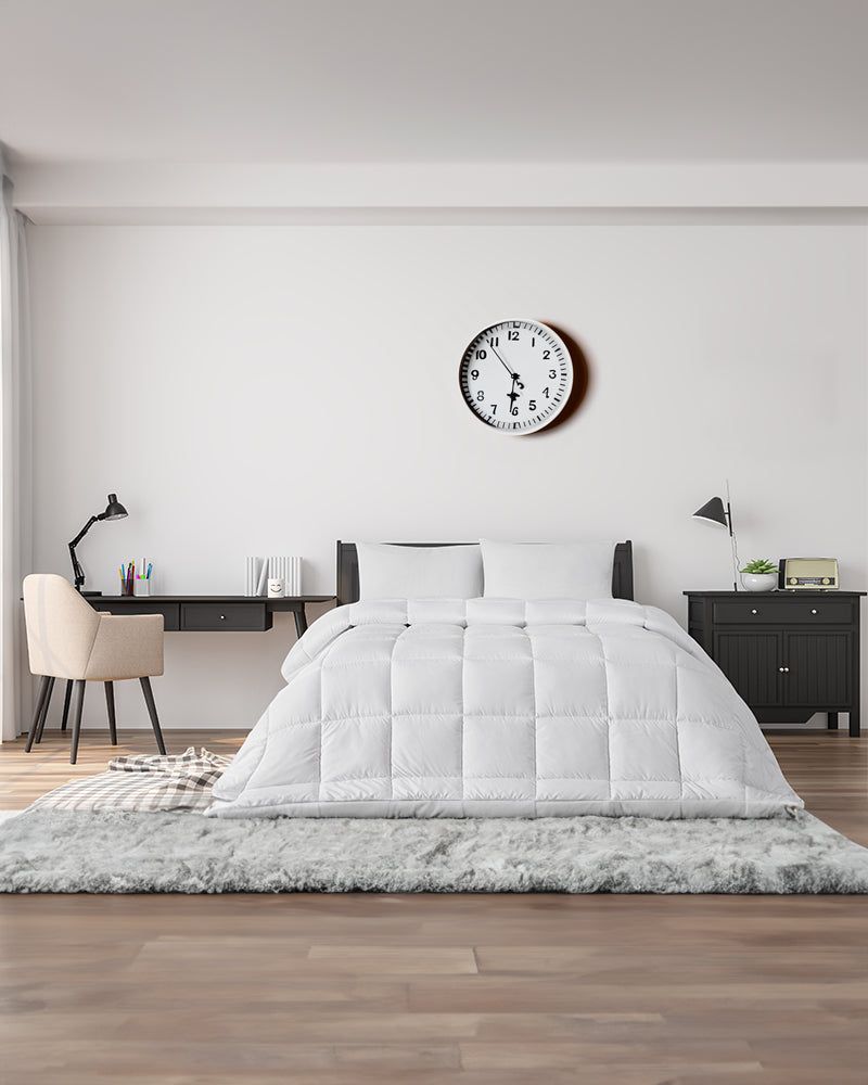 Minimalist bedroom with white bed, gray rug, desks, and a wall clock