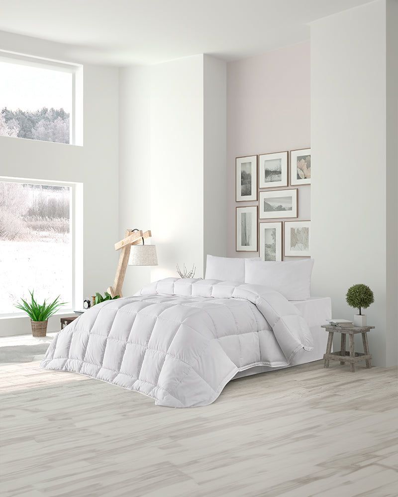 Bright white bedroom with a neatly made bed, large window, framed wall art, and light wood flooring