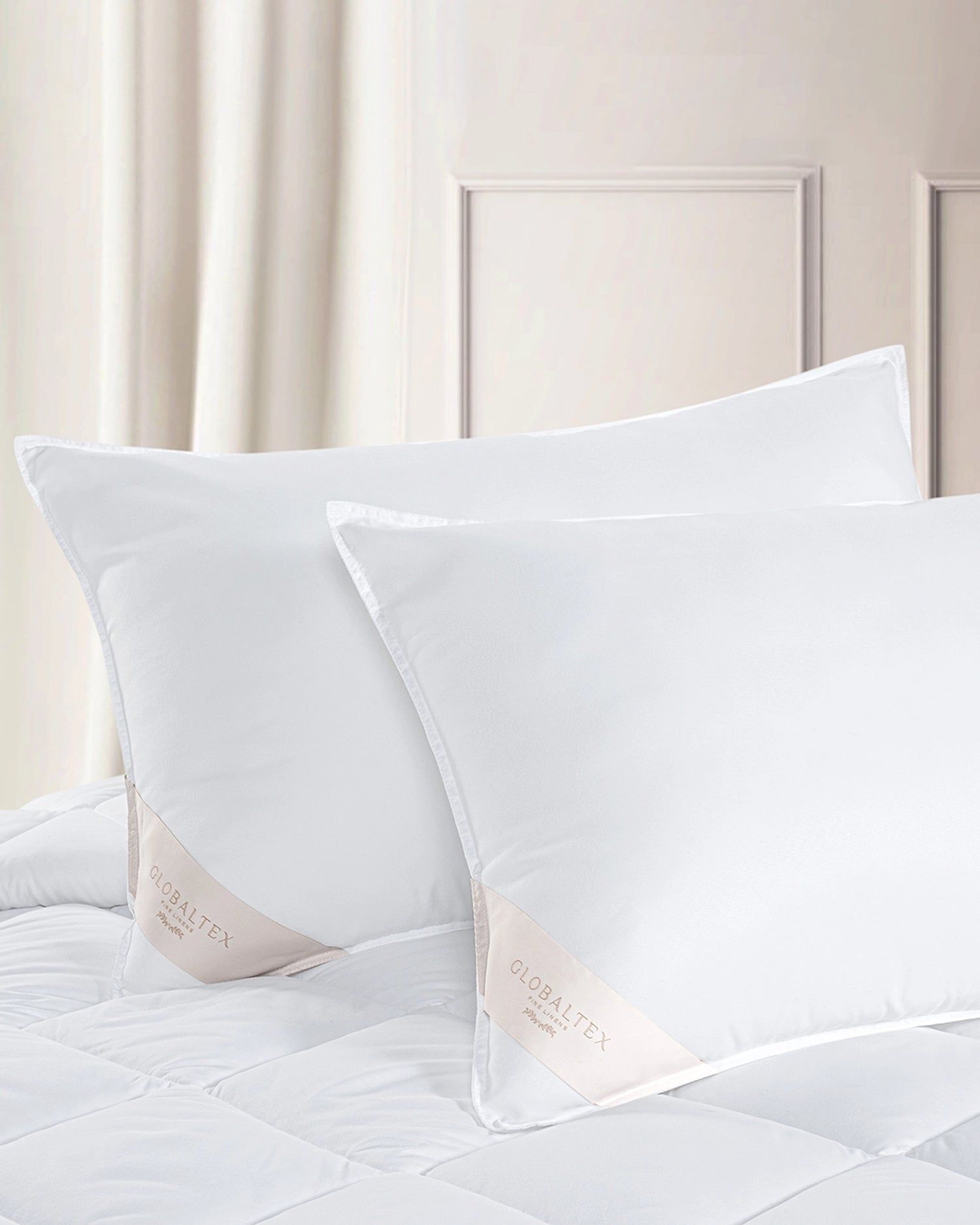 White pillows on a bed against a soft beige headboard and curtains