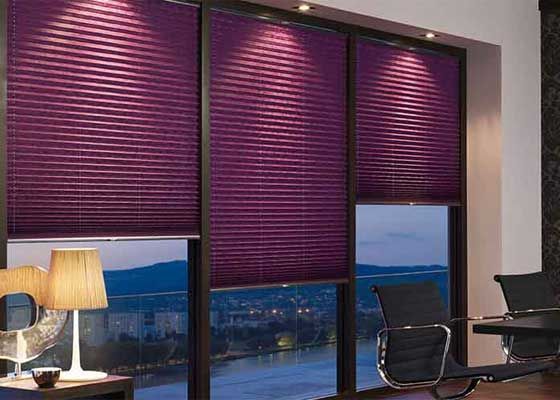 Office interior with purple blinds, large windows, desk lamp, and chairs overlooking a city view